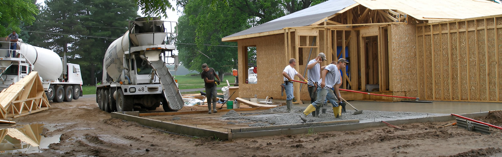 crew pouring concrete into driveway area